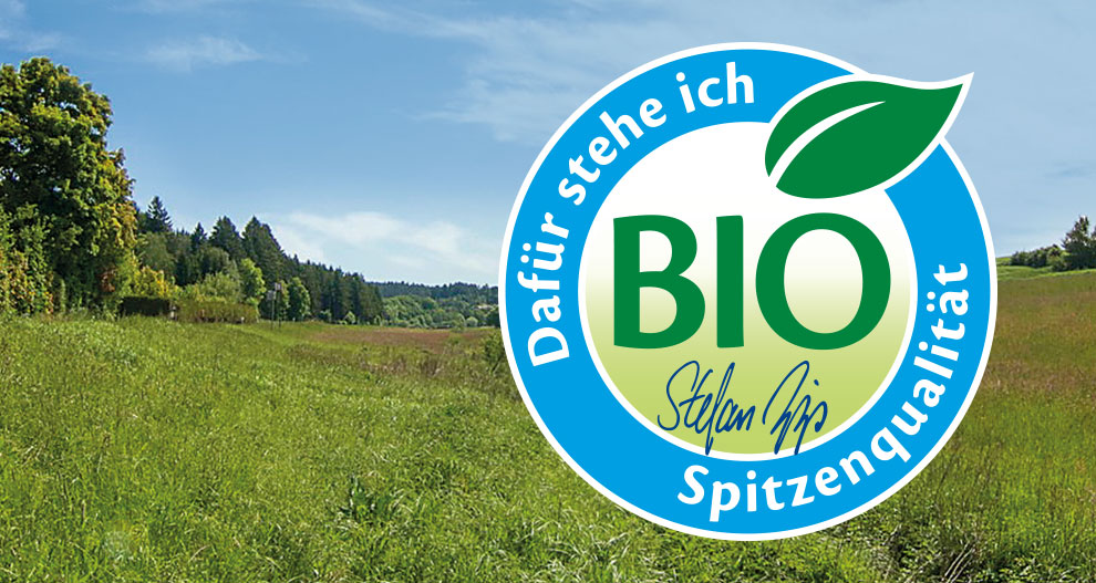 A lush green landscape with a blue sky is overlaid with a large circular bio logo.